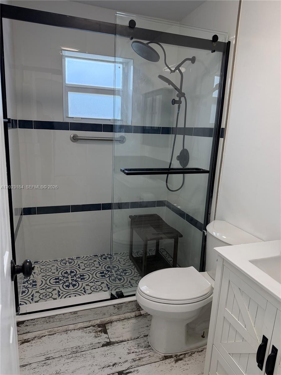 A bathroom features a glass-enclosed shower with patterned floor tiles and a white vanity — 3837 NE 17th Ave, Pompano Beach FL 33064, POMPANO BEACH, FL