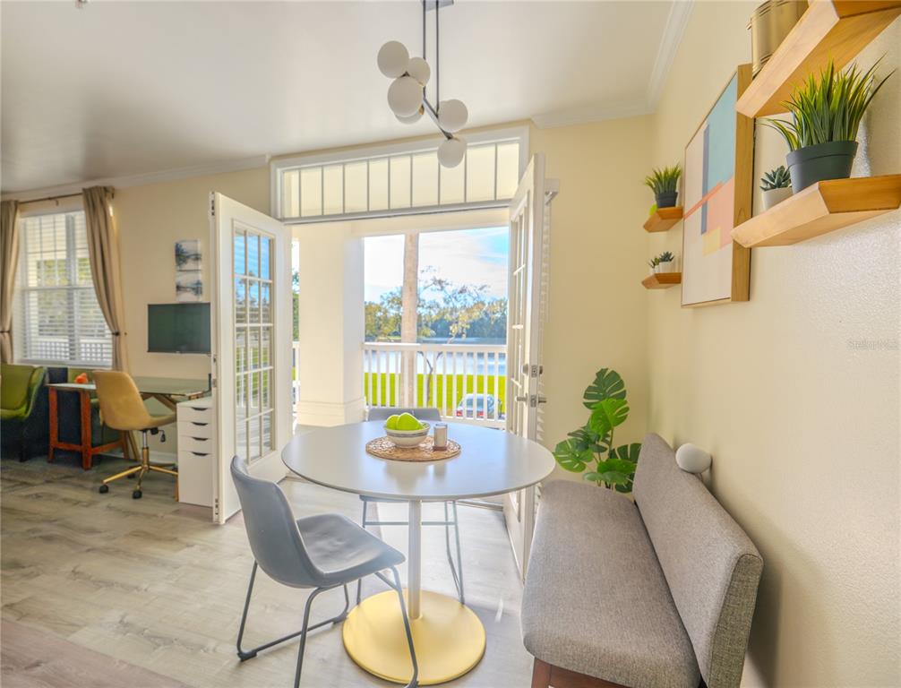 A dining area features a round table, a bench, and a chair near a balcony door — 770 SIENA PALM DRIVE UNIT 203, CELEBRATION, FL