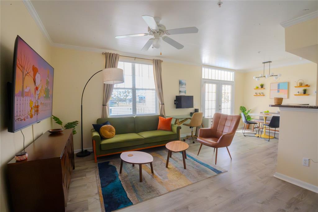 A living room features a green sofa, brown armchair, area rug, and a television — 770 SIENA PALM DRIVE UNIT 203, CELEBRATION, FL