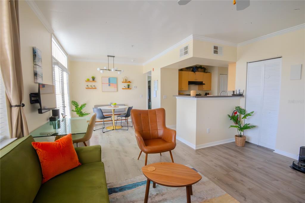 A living room with a green sofa, leather chair, and an adjacent dining area — 770 SIENA PALM DRIVE UNIT 203, CELEBRATION, FL