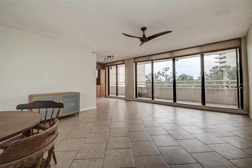 A spacious living area with tile flooring, a ceiling fan, and large sliding glass doors — 5940 PELICAN BAY PLAZA S UNIT 406, GULFPORT, FL