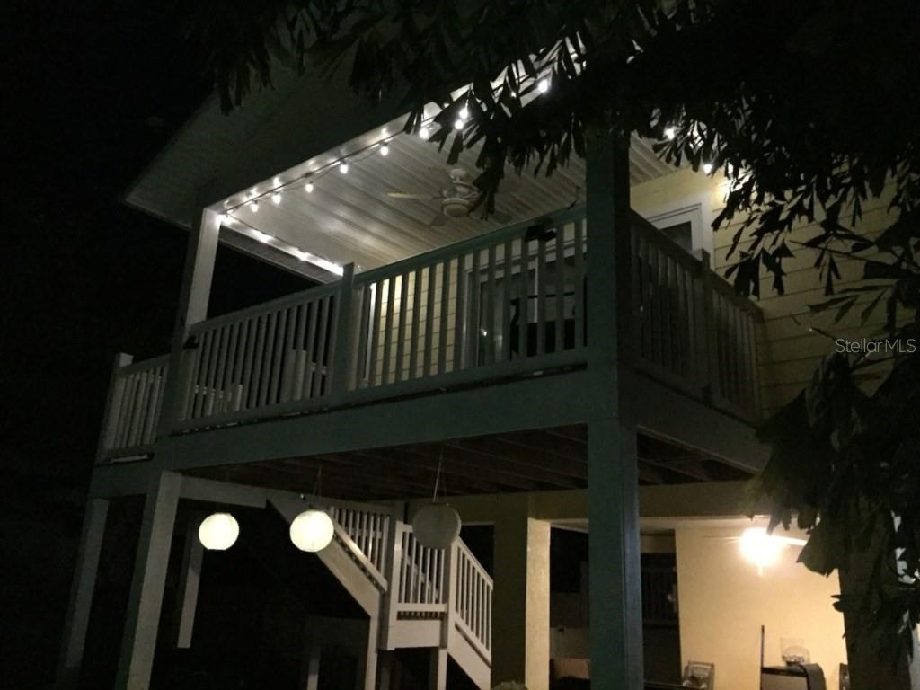 An elevated wooden deck with a ceiling fan and string lights at night — 303 62ND STREET UNIT A, HOLMES BEACH, FL
