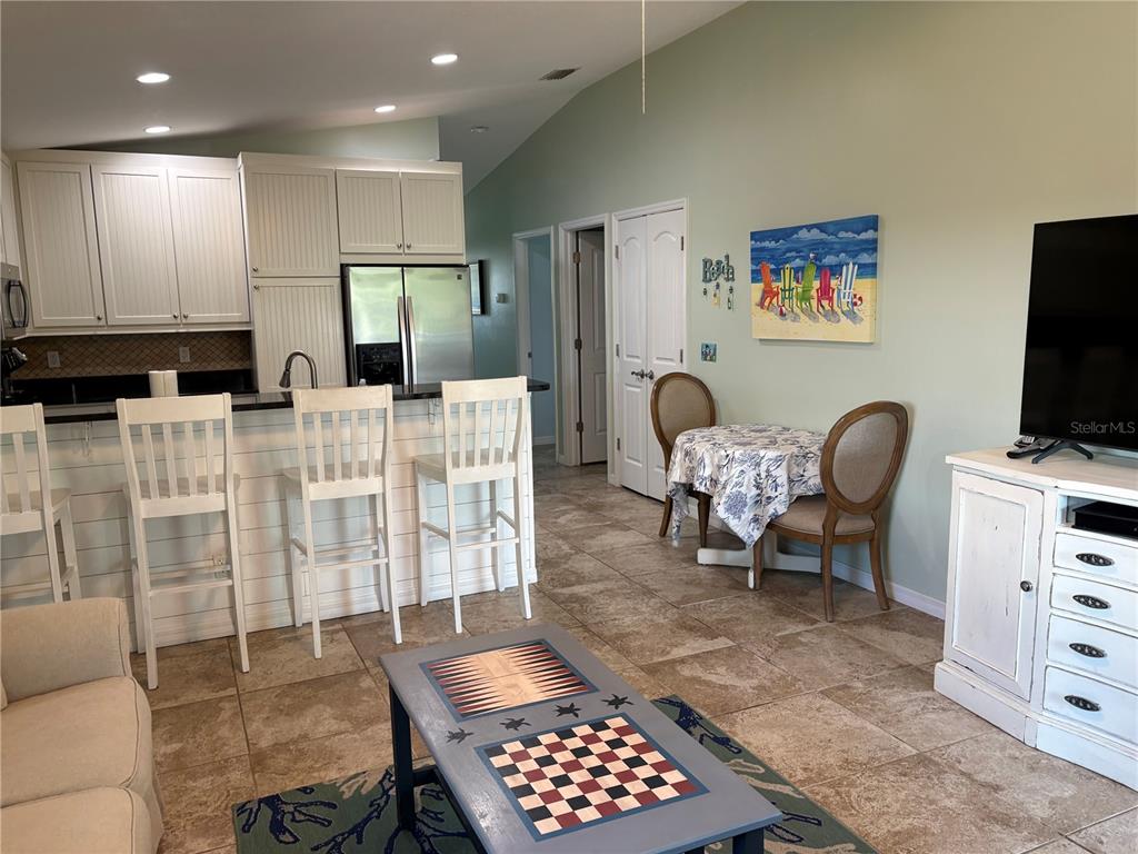 A kitchen with white cabinets and bar seating overlooks a living area with tile floors — 303 62ND STREET UNIT A, HOLMES BEACH, FL