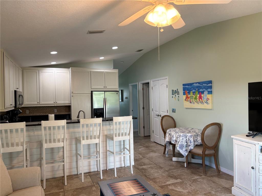 A kitchen with white cabinets and a breakfast bar overlooks a dining area and living room — 303 62ND STREET UNIT A, HOLMES BEACH, FL