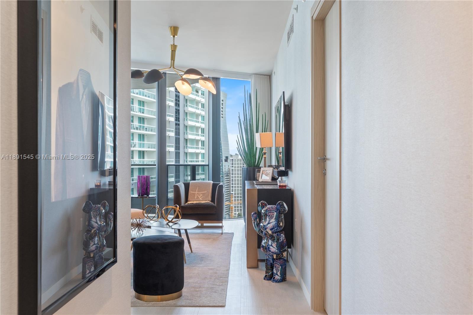 A modern living room features a chandelier, a dark armchair, and floor-to-ceiling city views — 1000 Brickell Plz # 3401, Miami FL 33131, MIAMI, FL