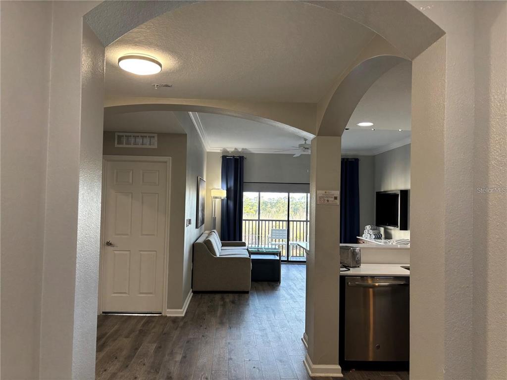 An arched entryway leads into a living area with a sofa, balcony, and kitchen — 14501 GROVE RESORT AVENUE UNIT 1503, WINTER GARDEN, FL