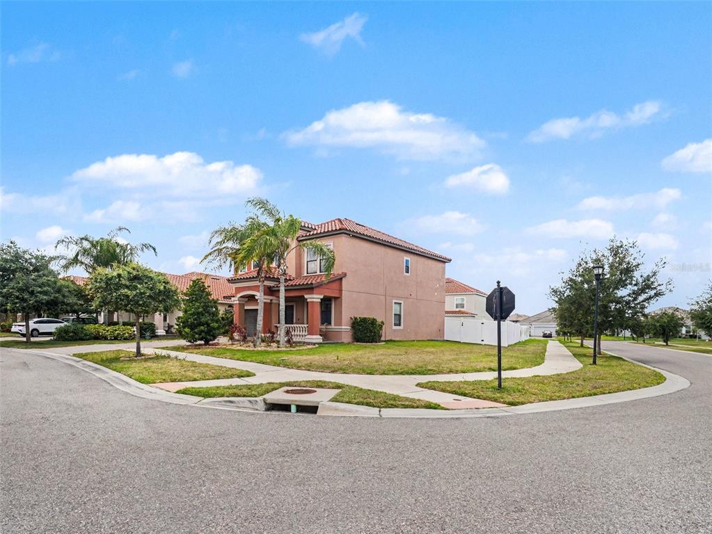 A two-story stucco house with a tile roof sits on a corner lot — 12027 CARDINAL FLOWER DR, RIVERVIEW, FL