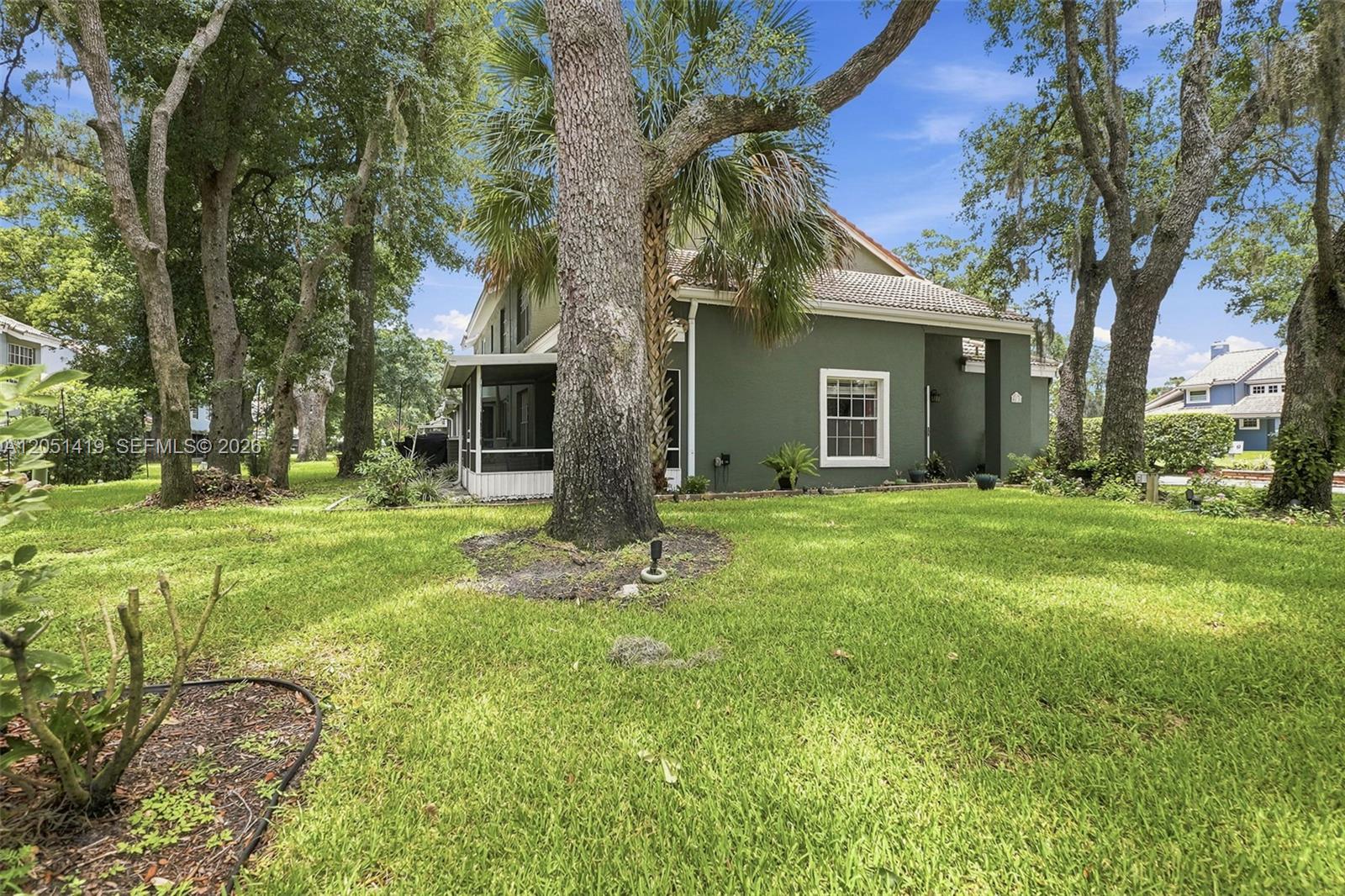 The exterior of a green house with a screened porch and large trees — 4478 Oak Arbor Circ, Orlando FL 33808, ORLANDO, FL