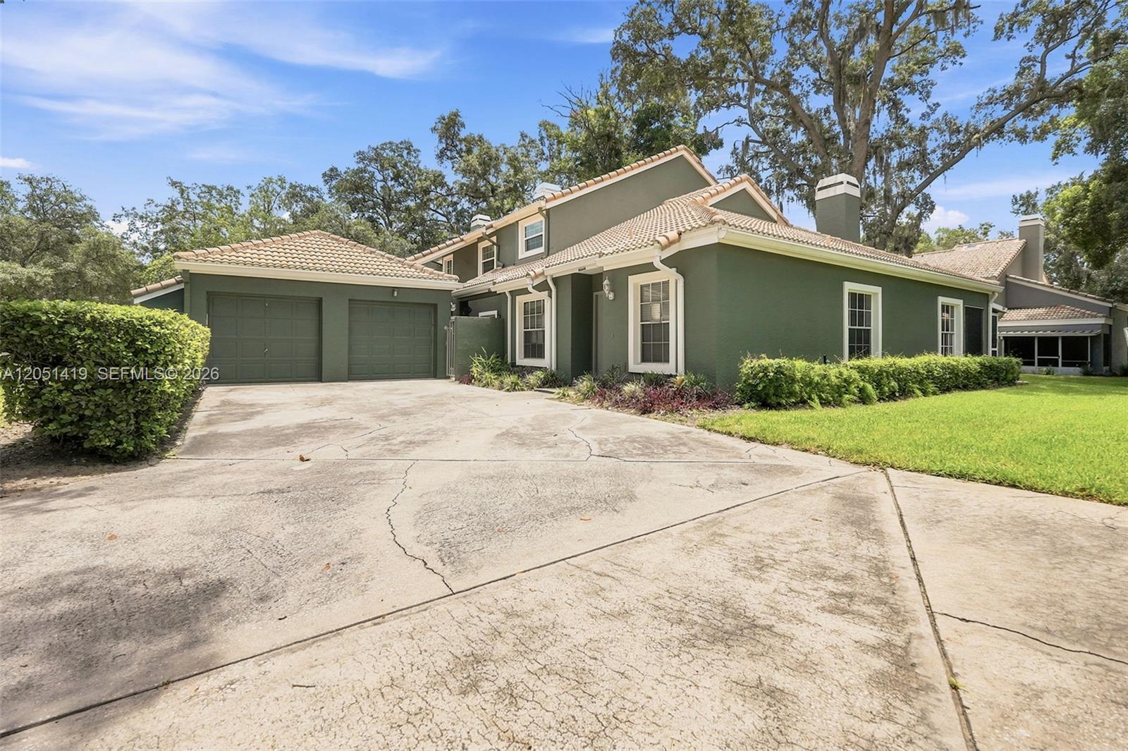 A two-story green house with a tile roof and a concrete driveway — 4478 Oak Arbor Circ, Orlando FL 33808, ORLANDO, FL