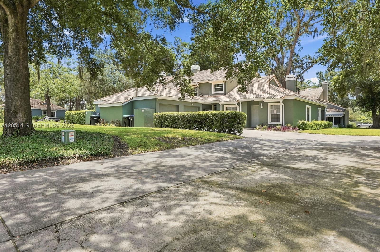 A green two-story house with a tile roof and a paved driveway under large trees — 4478 Oak Arbor Circ, Orlando FL 33808, ORLANDO, FL