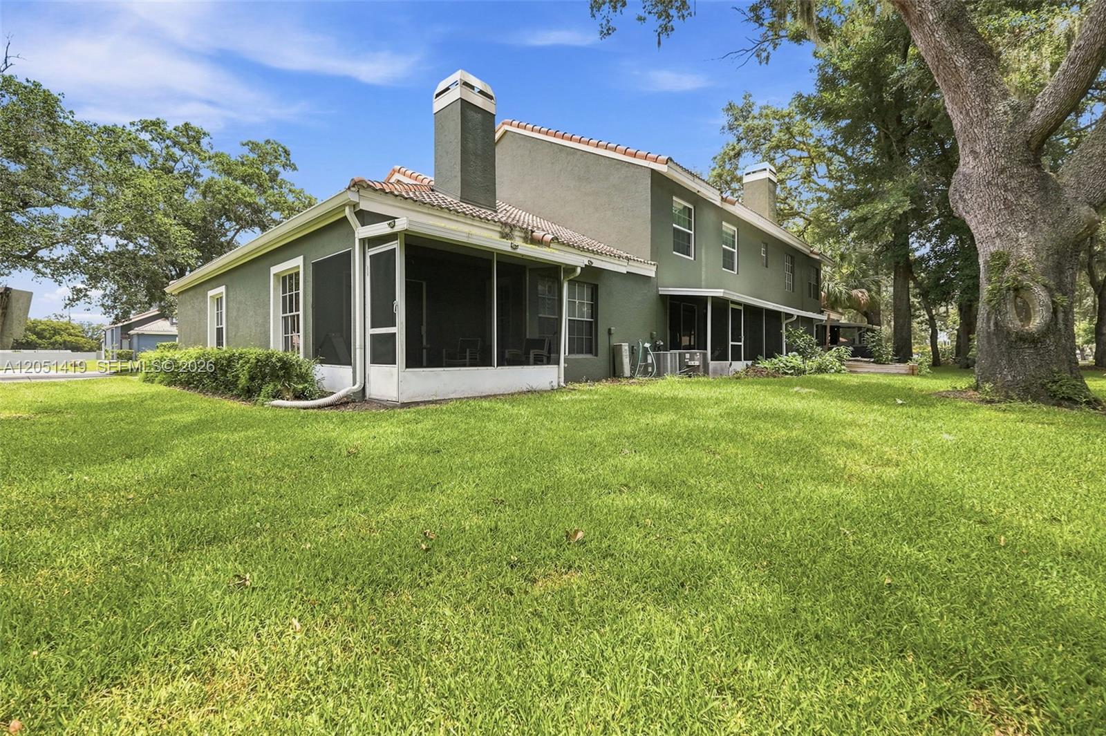The exterior of a two-story house features a screened-in porch and a large grassy yard — 4478 Oak Arbor Circ, Orlando FL 33808, ORLANDO, FL