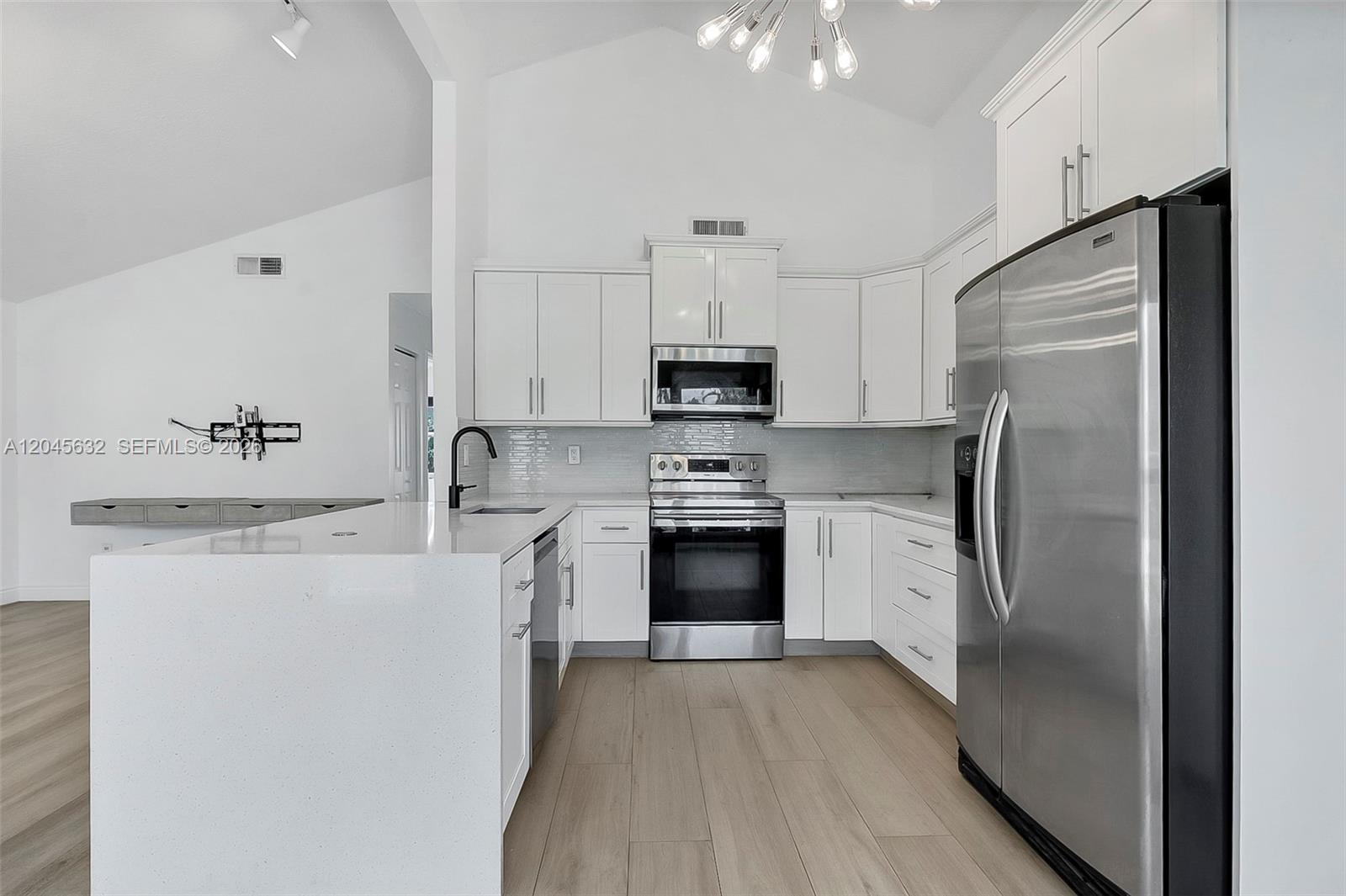 A modern kitchen features white cabinets, stainless steel appliances, and a white quartz island — 23384 Shetland Run, Boca Raton FL 33433, BOCA RATON, FL