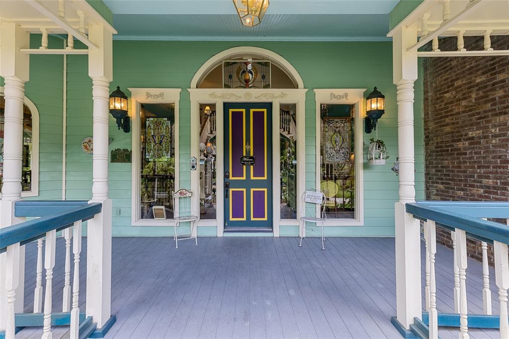 A front porch with a teal exterior, white columns, and a purple and gold front door — 6275 HALABRIN ROAD, HAINES CITY, FL