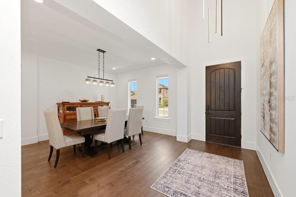 A dining area with a wooden table and chairs sits next to a high-ceilinged entryway — 8426 MOREHOUSE DRIVE, ORLANDO, FL
