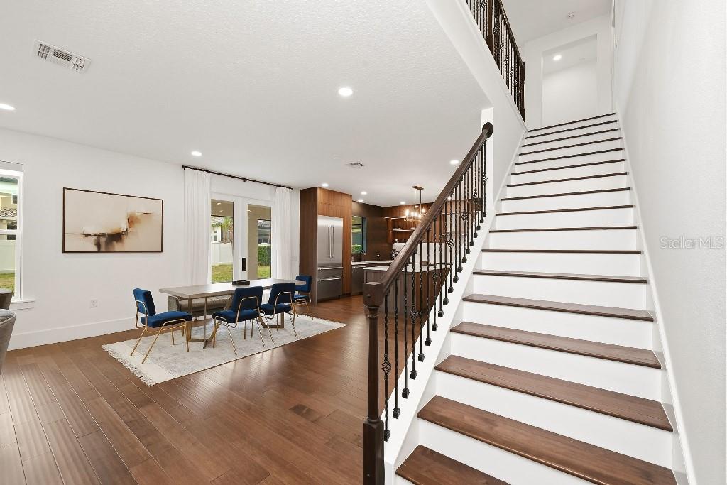 A modern dining area and kitchen are visible next to a staircase with dark wood treads — 8426 MOREHOUSE DRIVE, ORLANDO, FL