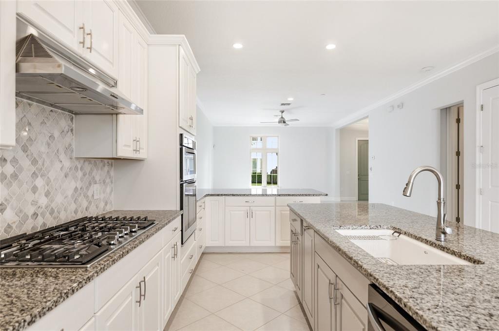 A kitchen with white cabinets, granite countertops, a gas cooktop, and a center island — 8807 FOUNTAIN PALM ALY, WINTER GARDEN, FL