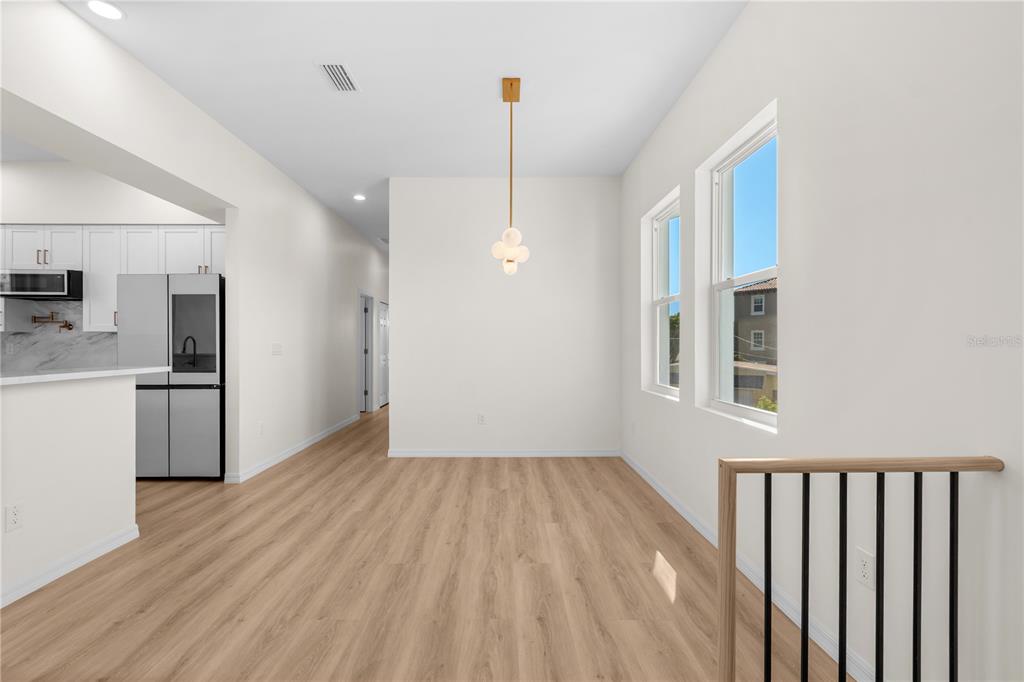 A dining area with light wood floors, a modern pendant light, and two windows — 4234 4TH STREET S, ST PETERSBURG, FL