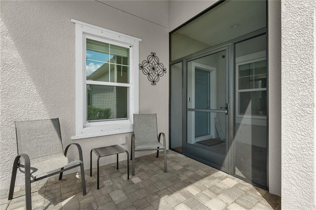 A covered patio features two chairs, a small table, a window, and a screen door — 2918 BUTTERFLY JASMINE TRAIL, SARASOTA, FL