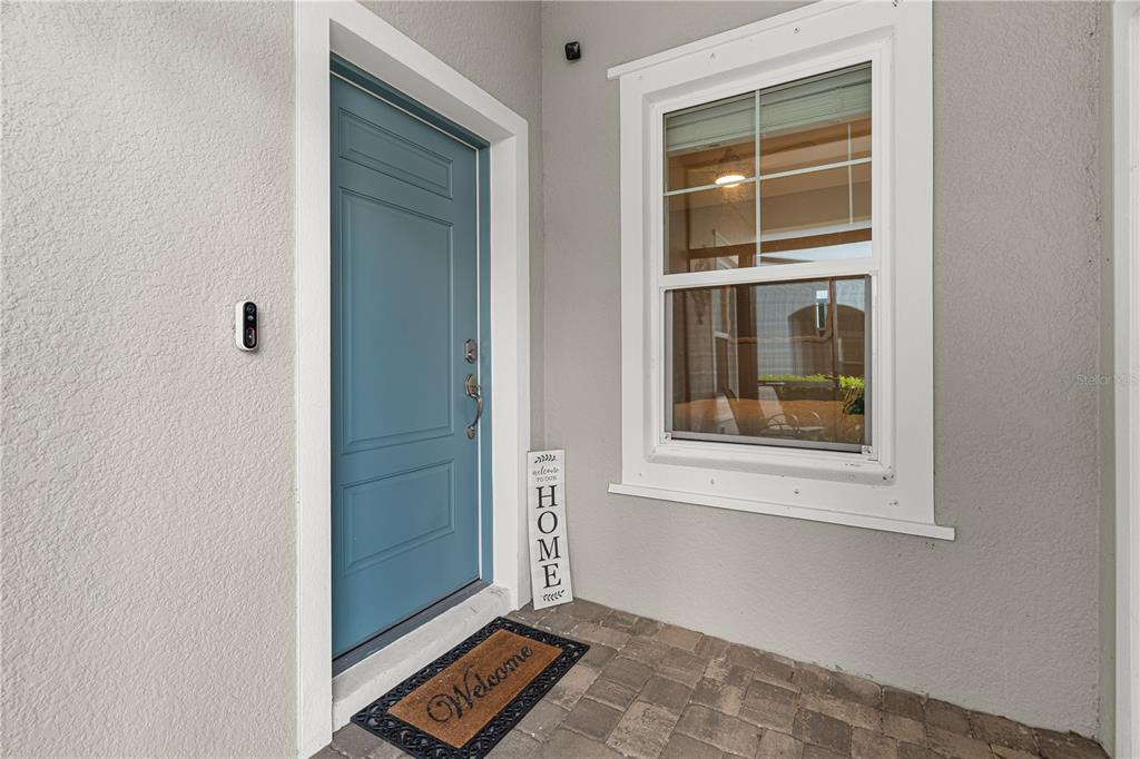 A blue front door and a window are visible on a paved porch area — 2918 BUTTERFLY JASMINE TRAIL, SARASOTA, FL