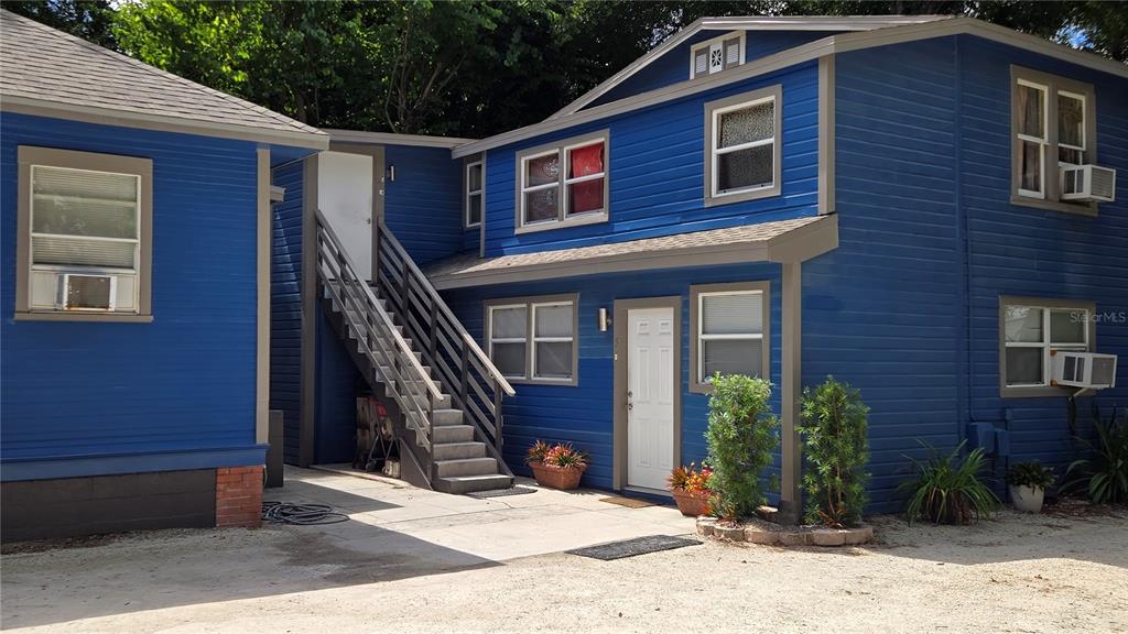 A two-story blue house with a white door, exterior staircase, and gravel driveway — 2306 N MORGAN STREET, TAMPA, FL