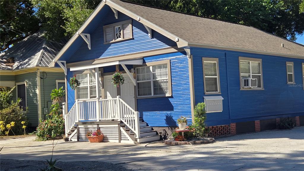 A blue, single-story house with a front porch and white trim sits on a gravel lot — 2306 N MORGAN STREET, TAMPA, FL