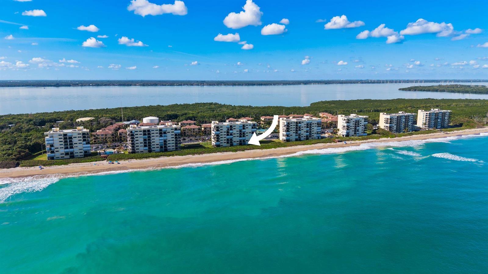 An aerial view shows several beachfront condominium buildings along a coastline with turquoise water — 7420 S Ocean # 113, Jensen Beach FL 34957, JENSEN BEACH, FL