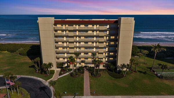 An aerial view of a multi-story beachfront condominium building surrounded by palm trees and grass — 7420 S Ocean # 113, Jensen Beach FL 34957, JENSEN BEACH, FL