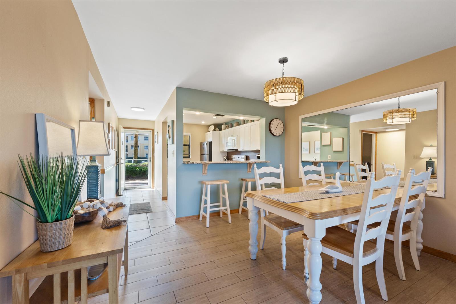 A dining area with a wooden table, white chairs, and a pass-through to the kitchen — 7420 S Ocean # 113, Jensen Beach FL 34957, JENSEN BEACH, FL