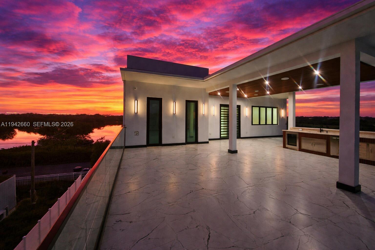A modern rooftop terrace features marble-look tile flooring, a covered outdoor kitchen, and sunset views — 141 Grassy Rd, Key Largo FL 33037, KEY LARGO, FL