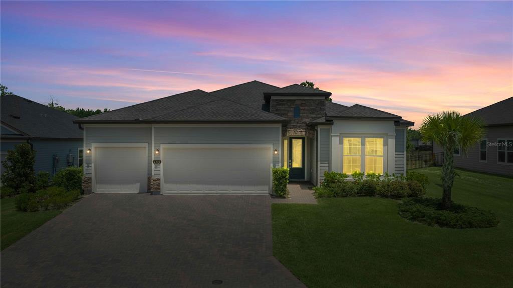 A single-story house with a three-car garage and stone accents under a sunset sky — 4227 SE 11TH AVENUE, OCALA, FL