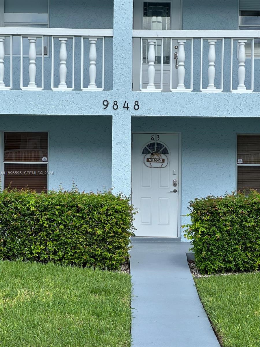 A blue two-story building exterior features a white front door labeled 83 and landscaping — 9848 Marina Blvd # 811, Boca Raton FL 33428, BOCA RATON, FL