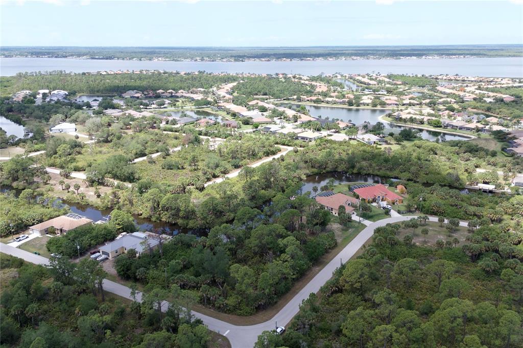 An aerial view shows houses nestled among trees and ponds near a large body of water — 13461 PULLEN AVENUE, PORT CHARLOTTE, FL