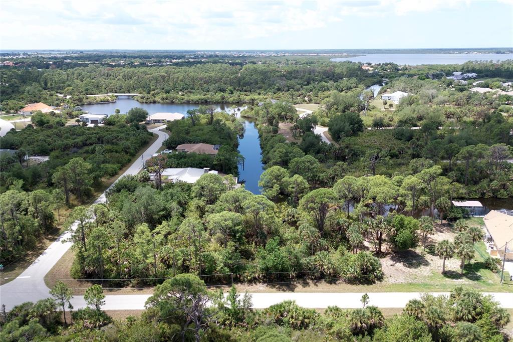 An aerial view shows a canal winding through a wooded residential area near a lake — 13461 PULLEN AVENUE, PORT CHARLOTTE, FL