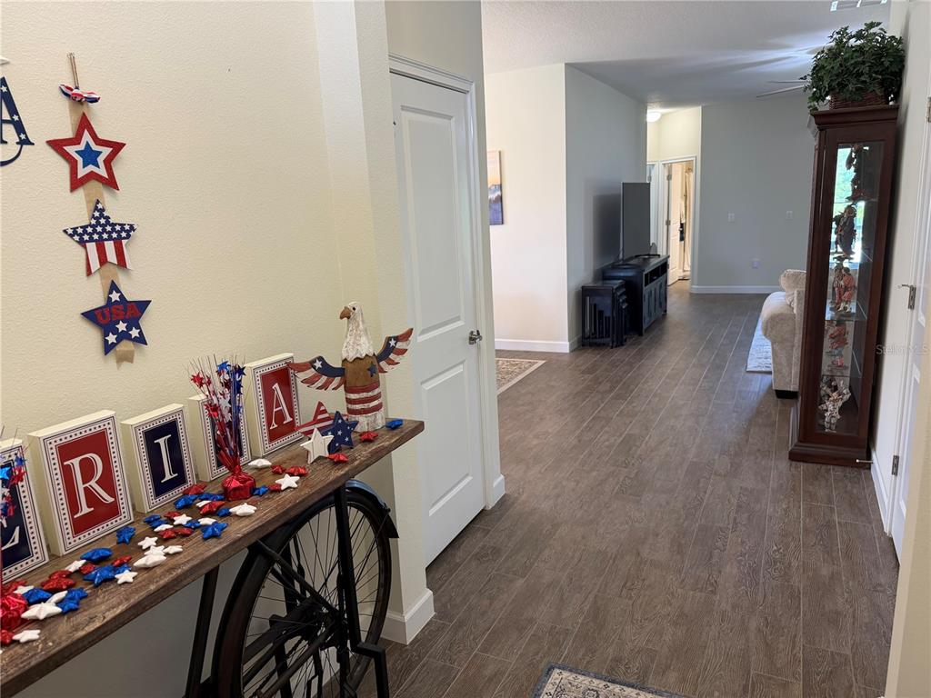 An entryway features a bicycle-base console table with patriotic decor, leading into a living area — 3572 KINLEY BROOKE LANE, CLERMONT, FL