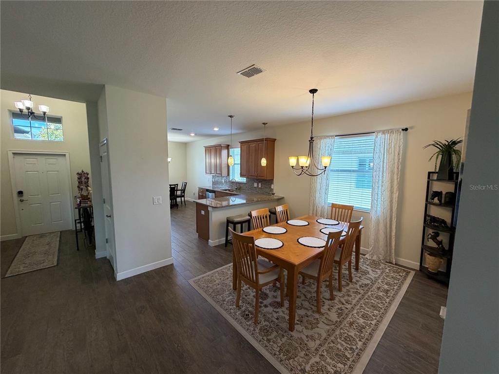 A dining area with a wooden table and chairs sits adjacent to an open kitchen — 3572 KINLEY BROOKE LANE, CLERMONT, FL