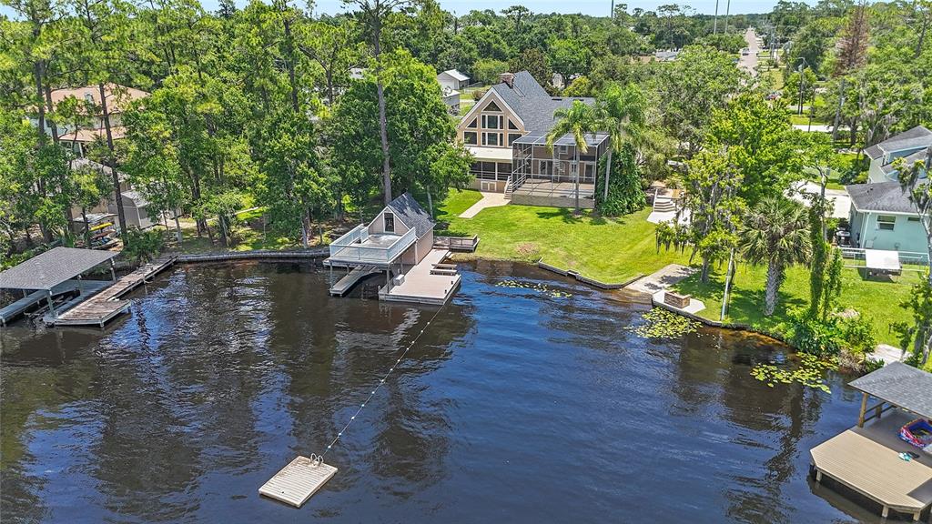 An aerial view shows a waterfront house with a dock, boat house, and grassy yard — 240 W 7TH STREET, CHULUOTA, FL