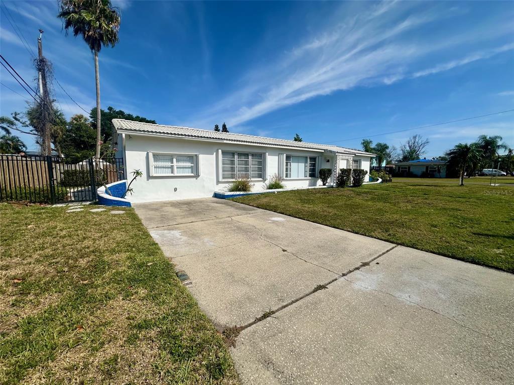 A single-story white house with a concrete driveway and a large front lawn — 10 158TH AVENUE, REDINGTON BEACH, FL