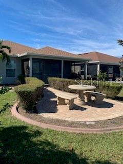 A stone patio with a table and bench sits outside a house with a screened porch — 9975 BISHOP CREEK WAY, PUNTA GORDA, FL