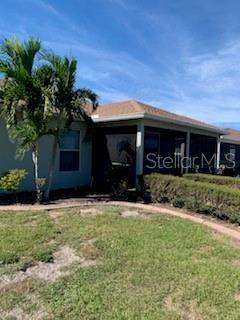 A view of a house exterior featuring a palm tree, a screened-in porch, and landscaping — 9975 BISHOP CREEK WAY, PUNTA GORDA, FL