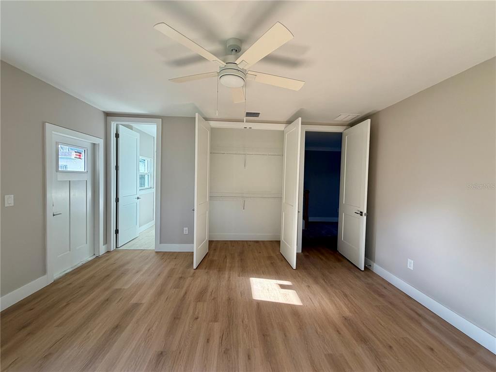 A room with light wood-look flooring, a ceiling fan, and open closet shelving — 4314 W GRAY STREET, TAMPA, FL