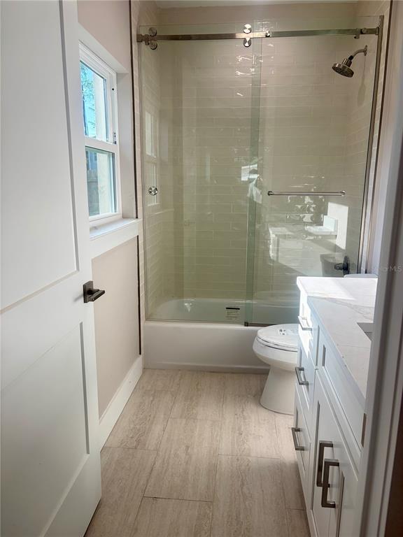 A bathroom features a glass-enclosed shower, a white vanity, and light-colored tile flooring — 4314 W GRAY STREET, TAMPA, FL