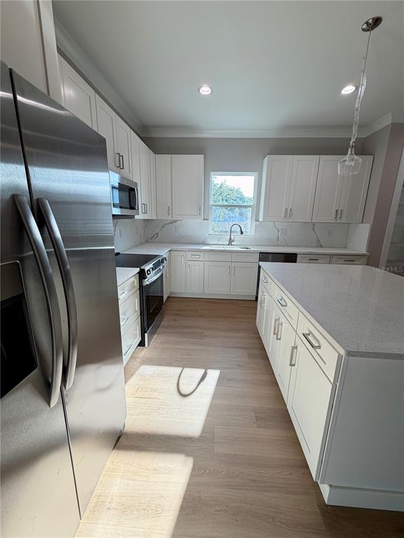 A modern kitchen features white cabinetry, stainless steel appliances, and a large quartz-topped island — 4314 W GRAY STREET, TAMPA, FL
