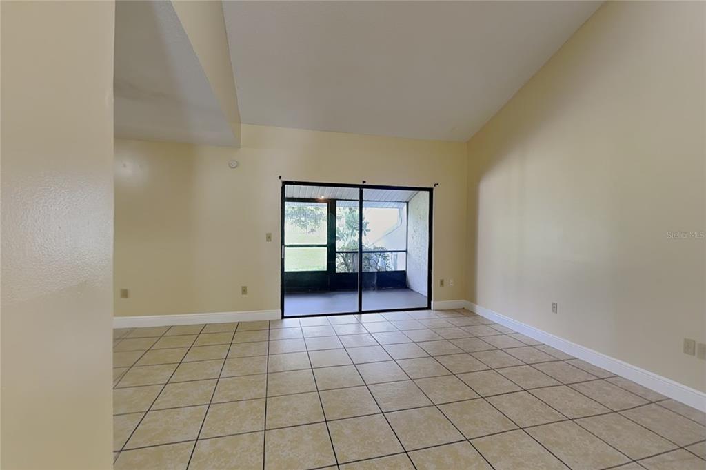 An empty room with beige tile flooring, light yellow walls, and a screened-in patio — 479 PRESTWICK PLACE, POINCIANA, FL