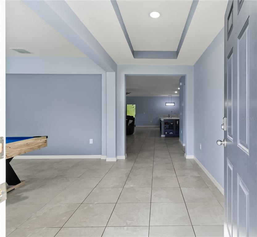A tiled entryway leads into a room with a pool table and a distant kitchen — 14557 CEDARWOOD AVENUE, WEEKI WACHEE, FL