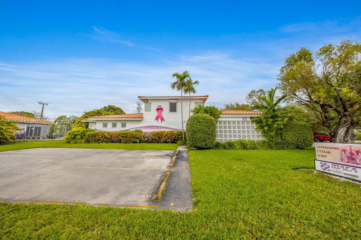 A two-story building with a pink ribbon mural sits behind a parking lot and lawn — 49 W 49TH St, Miami Beach FL 33012, MIAMI BEACH, FL