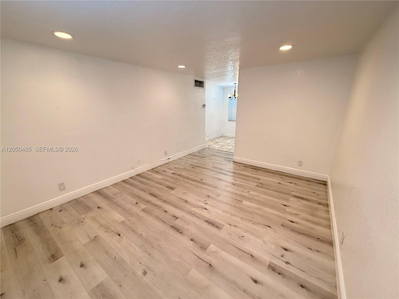 An empty room features light-colored wood-look flooring, white walls, and recessed ceiling lighting — 2826 Van Buren St # 2, Hollywood FL 33020, HOLLYWOOD, FL