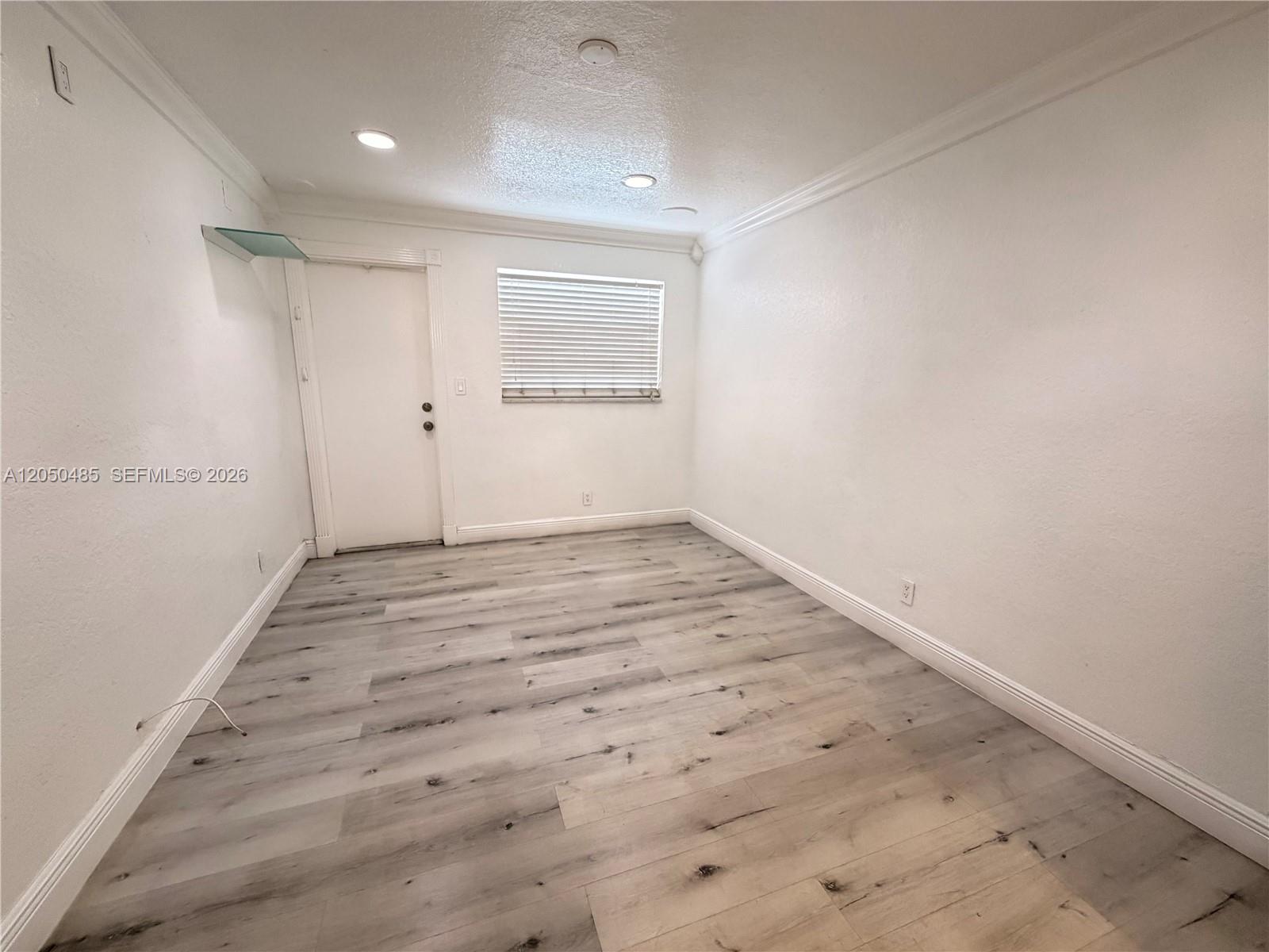 An empty room features white walls, crown molding, recessed lighting, and light-toned wood-look flooring — 2826 Van Buren St # 2, Hollywood FL 33020, HOLLYWOOD, FL