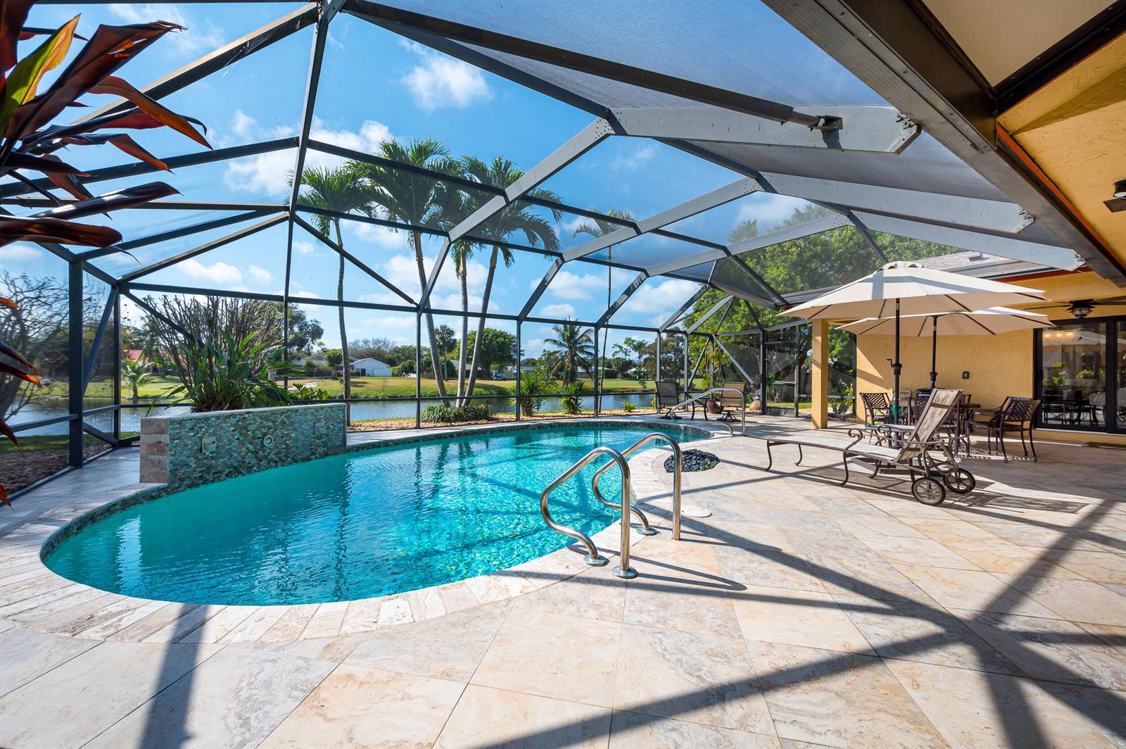 A screened-in patio features a swimming pool with a water feature and outdoor furniture — 3250 Lakeview Boulevard, Delray Beach FL 33445, DELRAY BEACH, FL