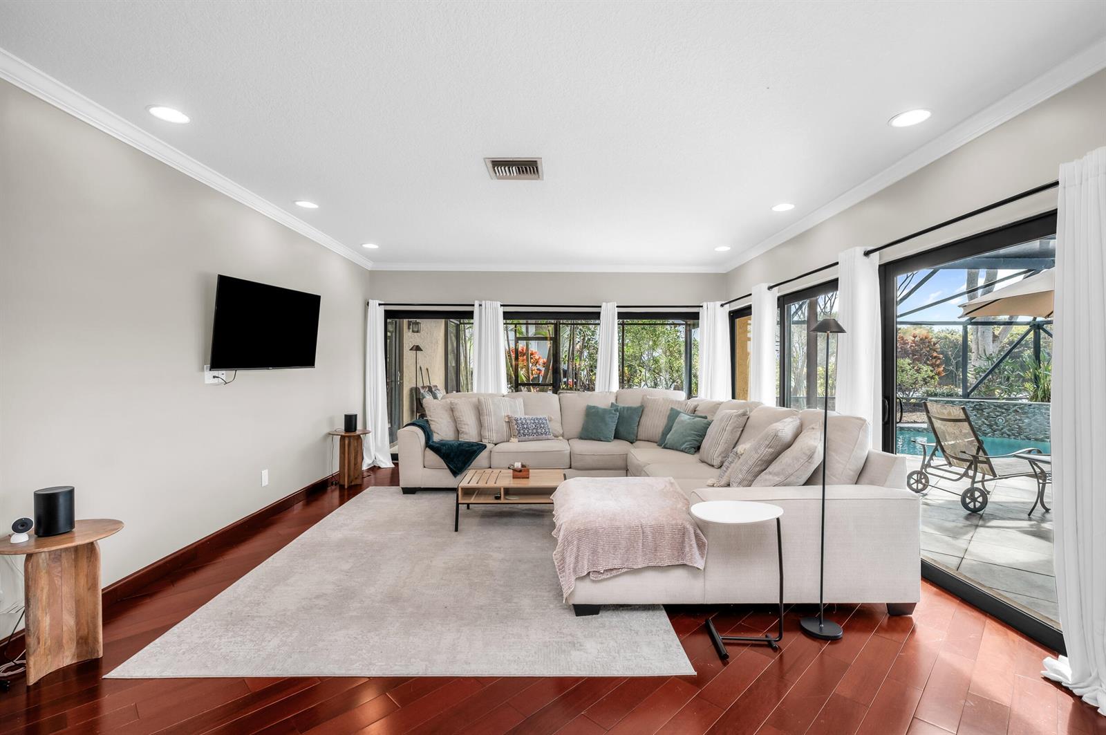 A living room features a large sectional sofa, hardwood floors, and sliding glass doors — 3250 Lakeview Boulevard, Delray Beach FL 33445, DELRAY BEACH, FL