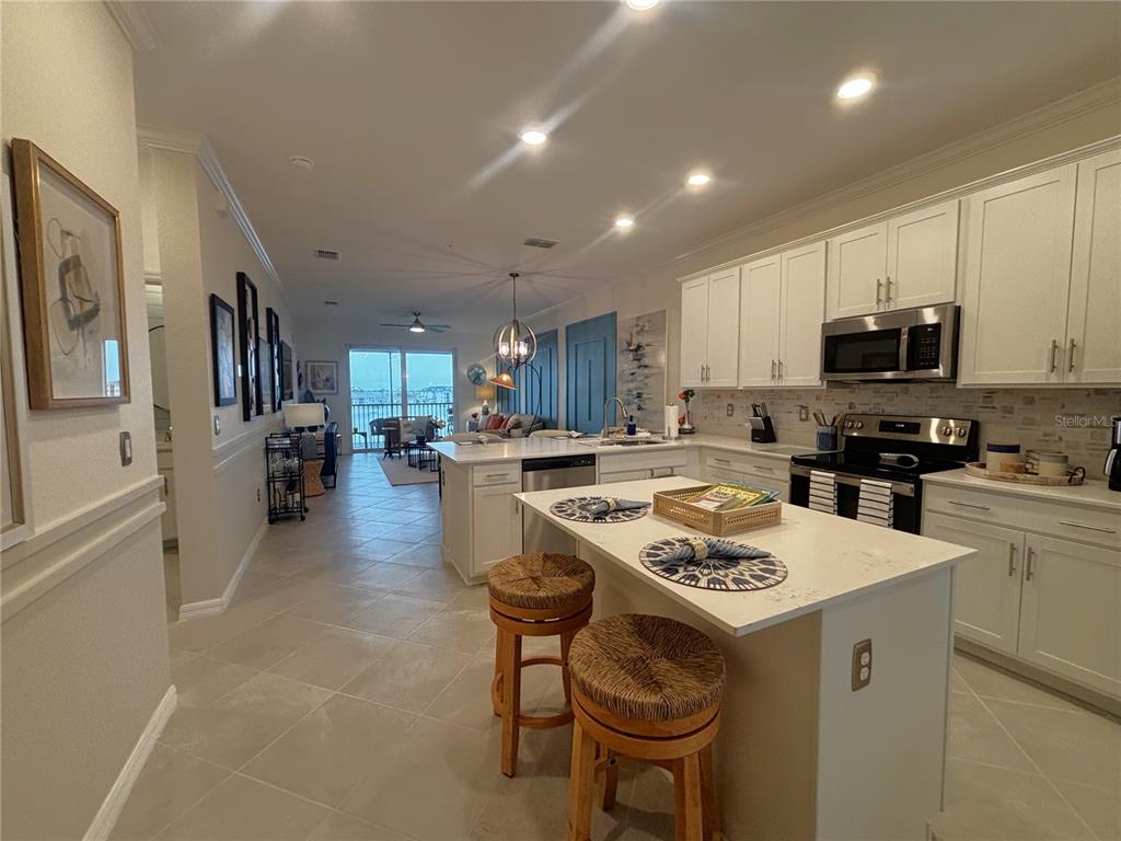 A kitchen with white cabinets and a central island overlooks an open-concept living area — 12140 WELLEN GOLF STREET UNIT 404, VENICE, FL